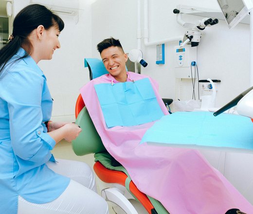 A dentist chatting with a smiling patient